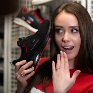 742561 – HANNAH XXTL BOA® black-red Low ESD S3S - junge Frau mit erstauntem Gesicht mit Blick auf einen Sicherheitsschuh von ELTEN