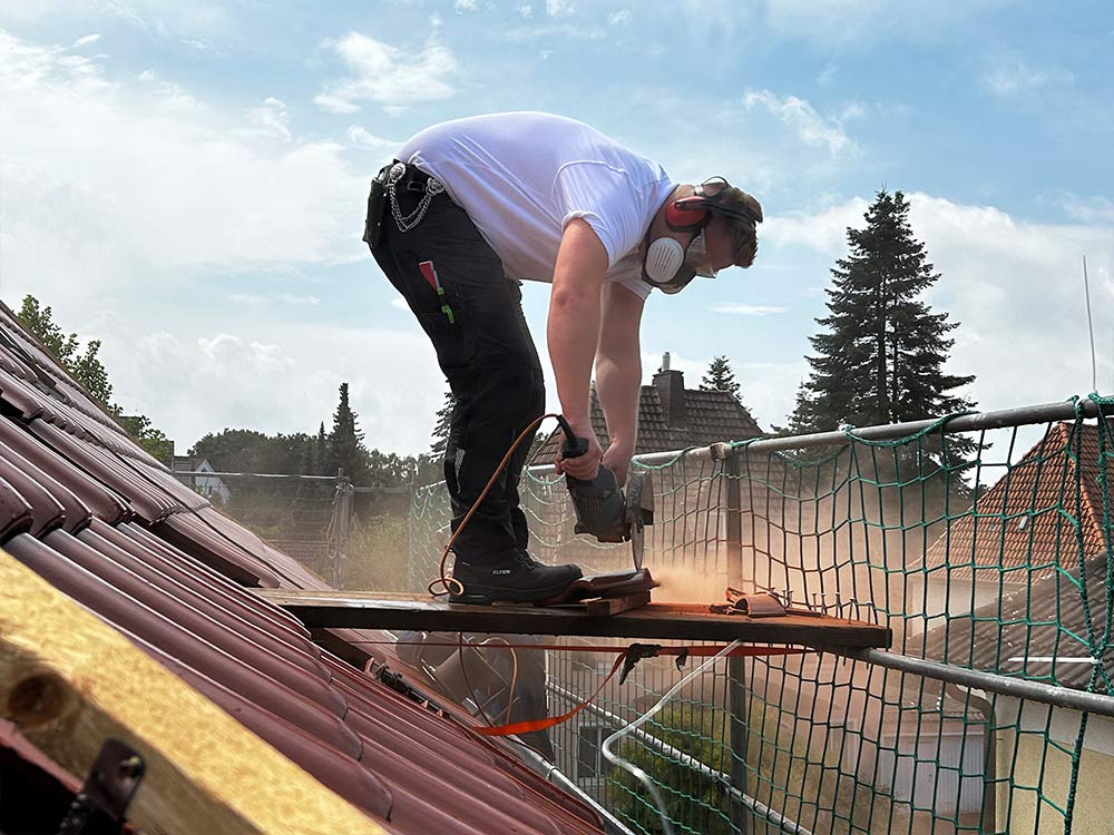 Dachdecker Christian Vogel auf dem Dach bei Sägearbeiten