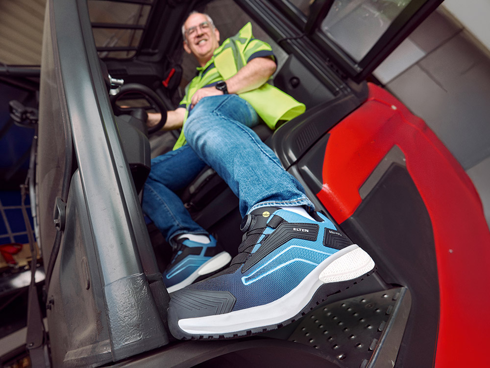 A man is sitting in a forklift truck and wearing safety shoes from Elten.